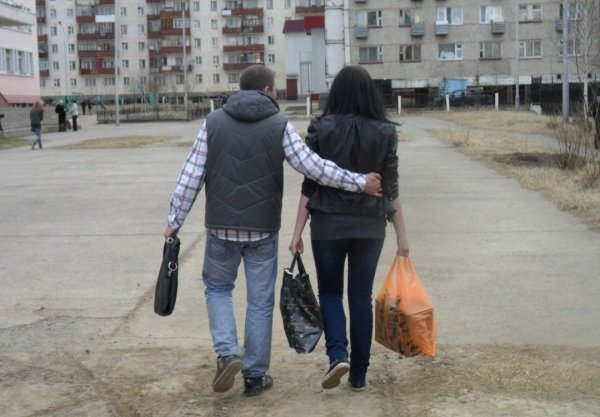 Женщина несет сумки а мужчина идет рядом