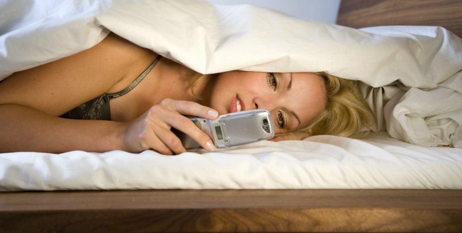 Девушка с телефоном в кровати