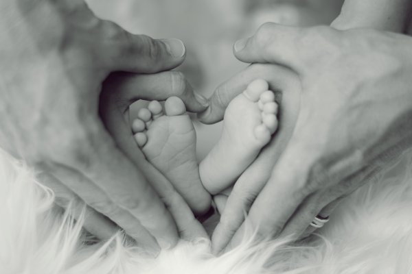 Ножки малыша в руках родителей